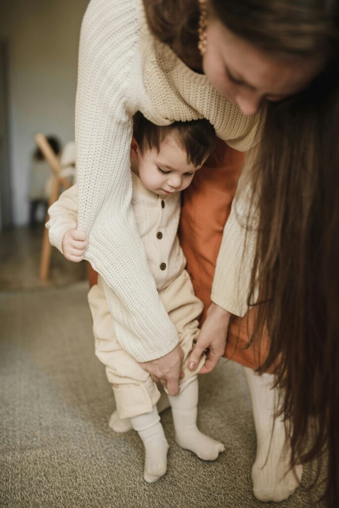 Mom assisting child in getting dressed, capturing a cozy indoor moment with selective focus.