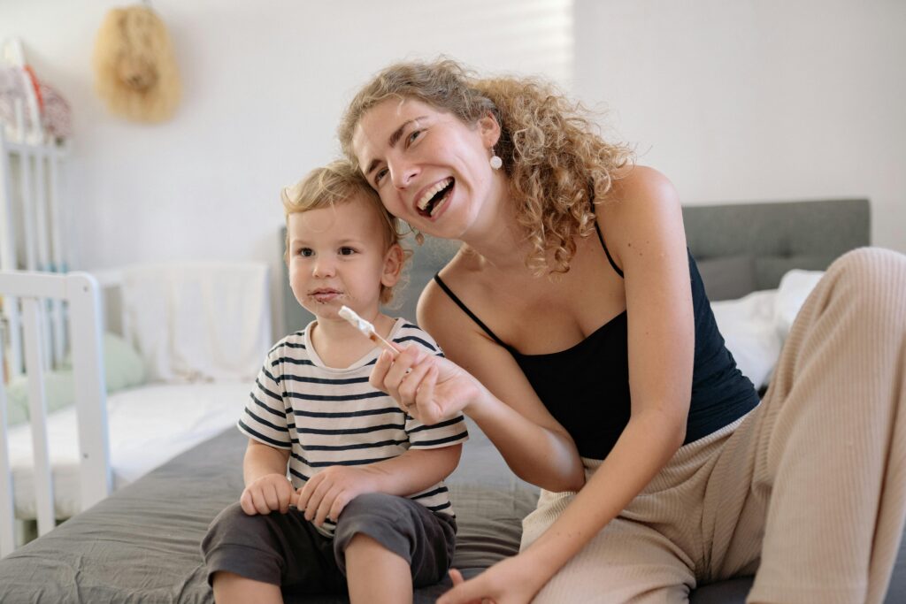 Happy mother and son smiling while eating ice cream indoors.