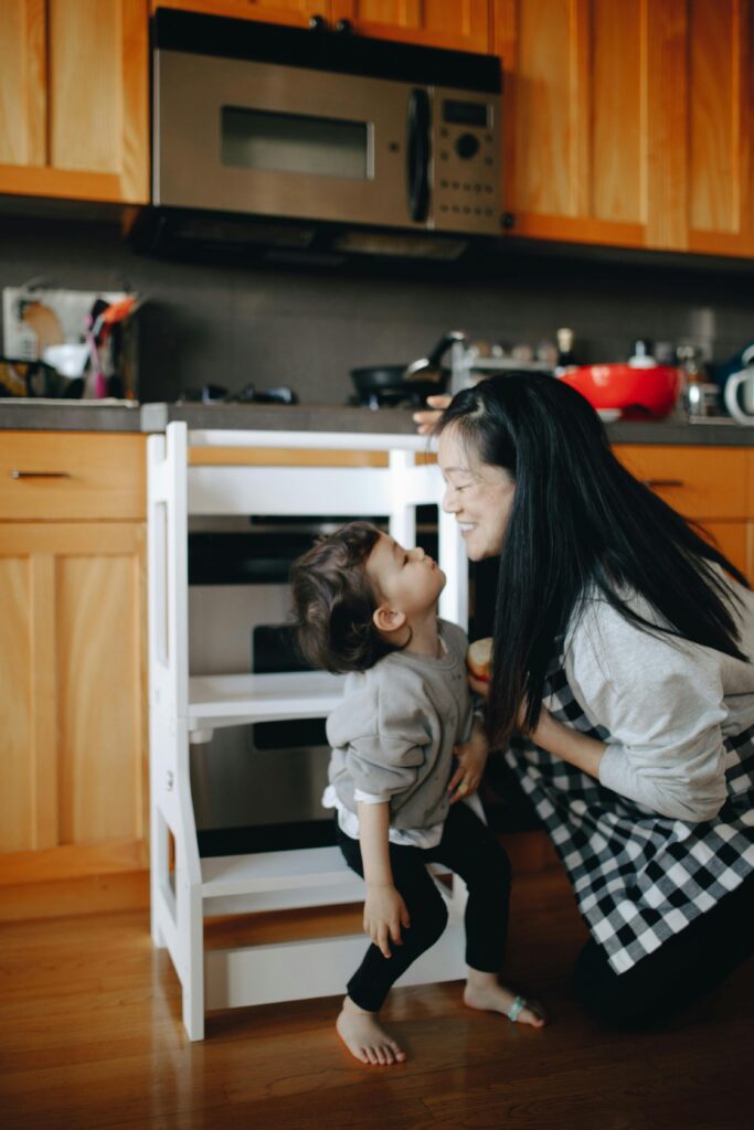 A mother and daughter share a joyful moment in a contemporary home kitchen.