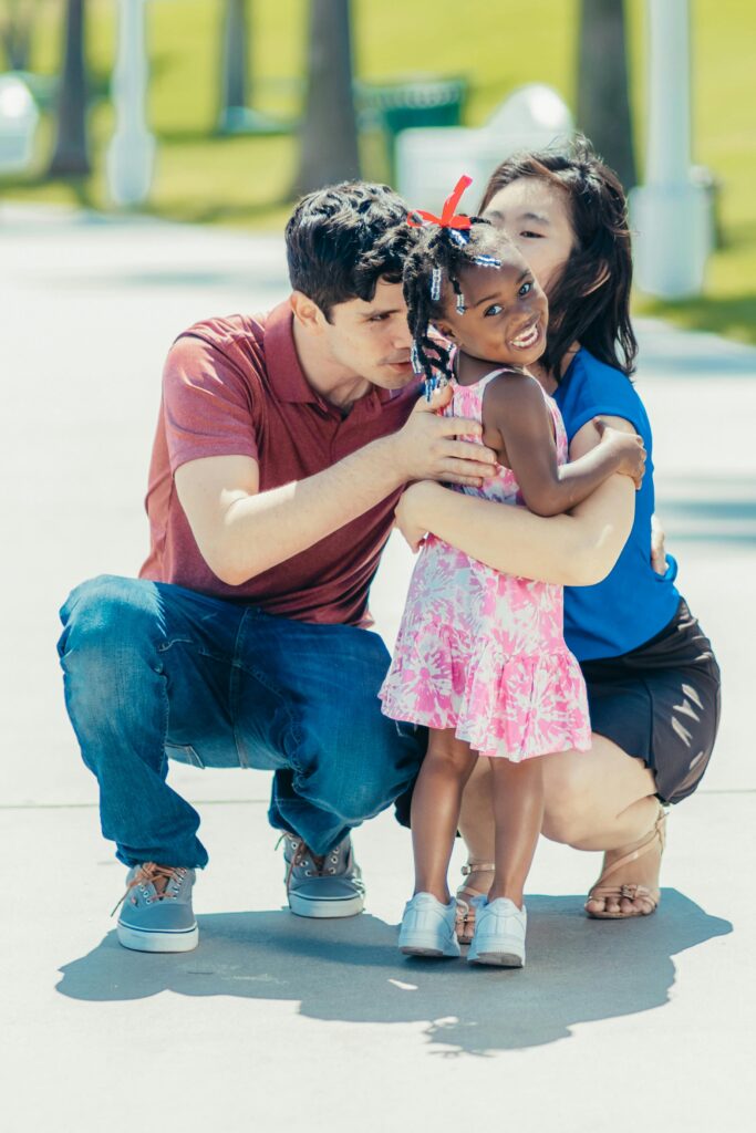 Joyful family bonding with parents embracing their daughter outdoors.